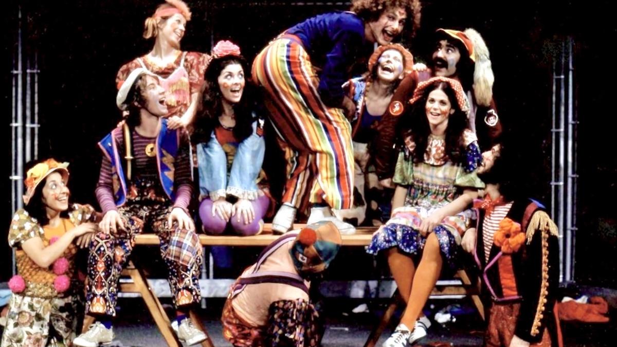 YOU HAD TO BE THERE, 2025, group of performers in colorful clown-like outfits and costumes on stage and gathered around