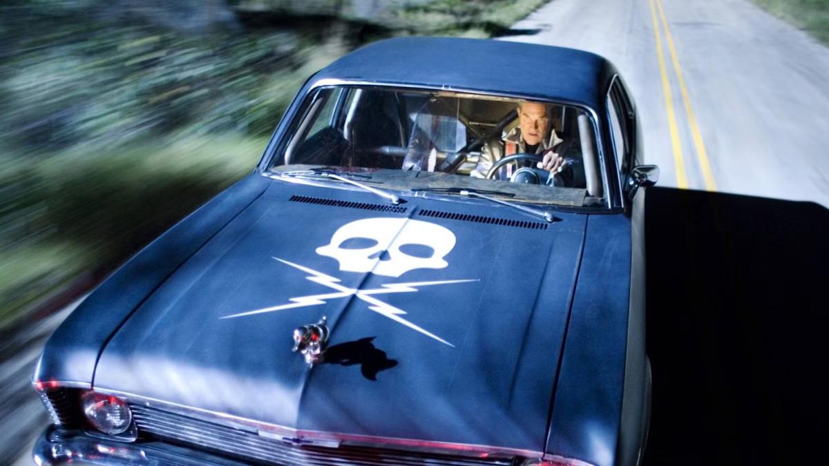 DEATH PROOF, 2007, man driving black car with skull and crossbones on hood
