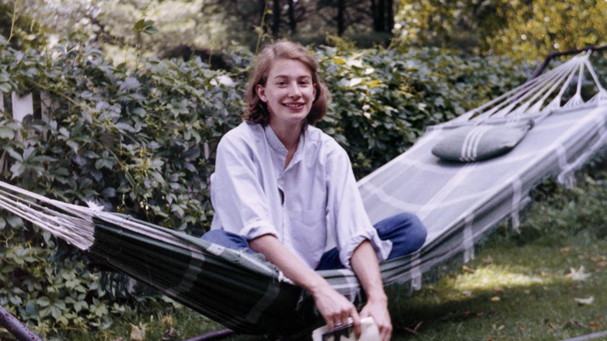 MARY OLIVER: SAVED BY THE BEAUTY OF THE WORLD, woman in white button down shirt seated in hammock in wooded yard