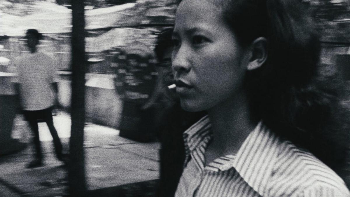 MYSTERIOUS OBJECT AT NOON, 2000, black and white image of woman in white shirt smoking cigarette on the street
