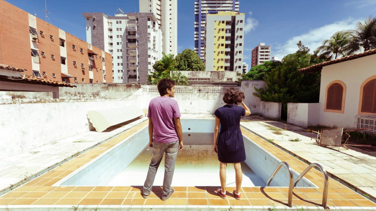NEIGHBORING SOUNDS, 2001, two people standing in front of empty pool in city looking into it