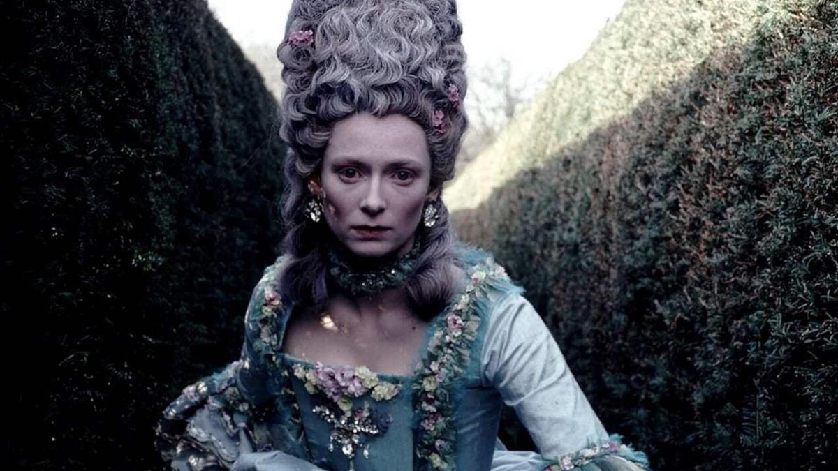 ORLANDO, 1992, woman in eighteenth century corset and dress with large wig running through garden