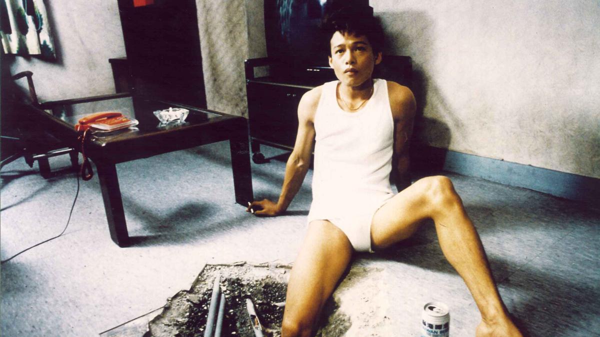 THE HOLE, 1998, man in white tank top and boxers leaning back on arms on apartment floor
