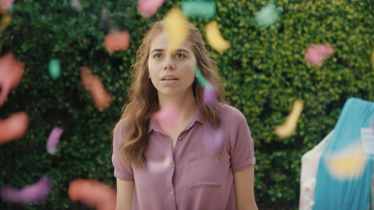 PUDDYSTICKS, 2025, girl in pink polo standing in yard with colorful confetti falling around her