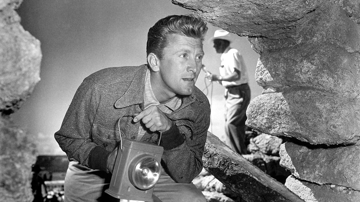 ACE IN THE HOLE, 1951, man in work jacket peering down cave with lantern