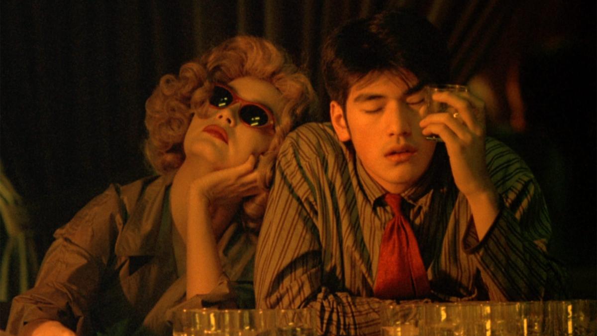 CHUNGKING EXPRESS, 1994, man and woman seated at dimly lit bar with woman wearing sunglasses and leaning on man's shoulder