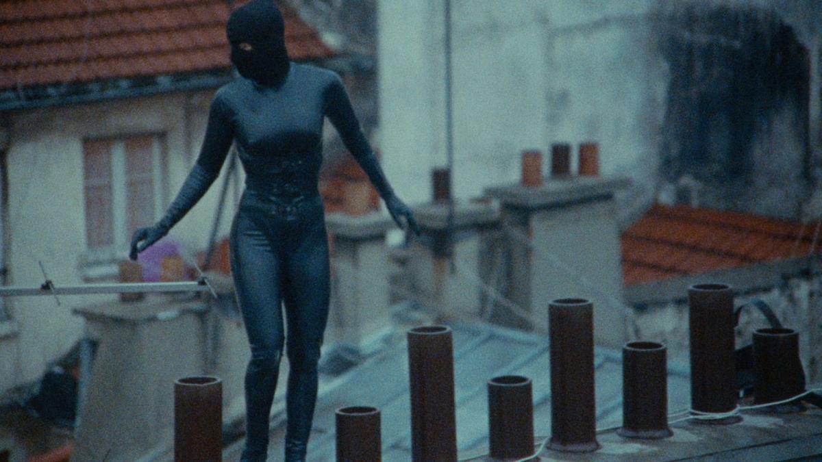 IRMA VEP, 1996, woman in leather suit and mask walking on top of building roof