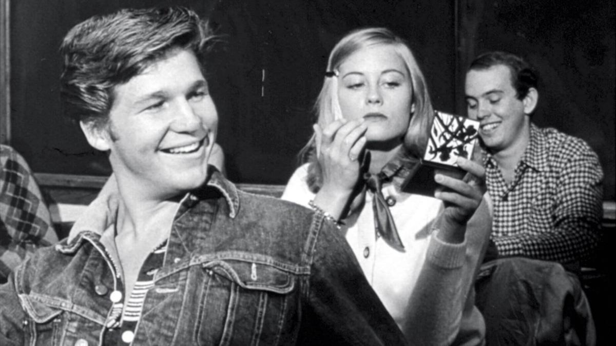 THE LAST PICTURE SHOW, 1971, black and white image of two young men and woman seated in a row with woman looking at self in compact mirror and man in front smiling