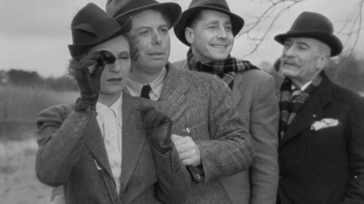 THE RULES OF THE GAME, 1939, black and white image of one woman and three men dressed in suit jackets and hats with woman holding spyglass up to eye and men looking out behind her
