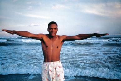 man with outstretched arms in front of ocean