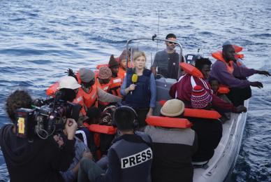 woman on raft with men and reporters in life vests