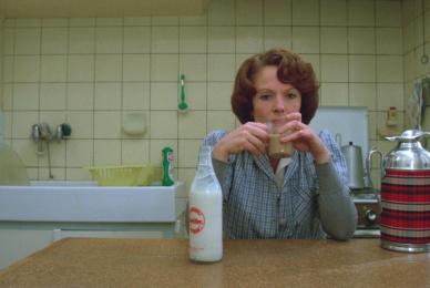 woman sitting at table drinking milk