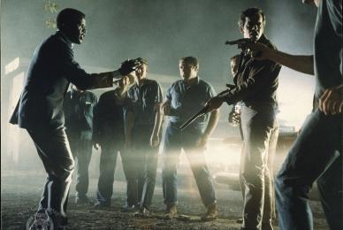 men gathered around with weapons cornering a man at night
