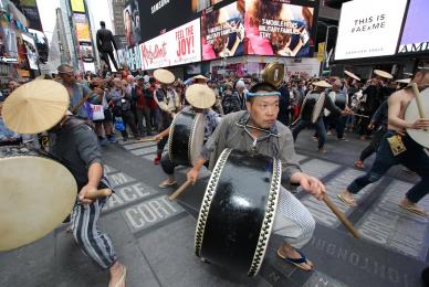 group of men playing drums while walking down city street