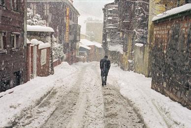 man walking through snowy city street