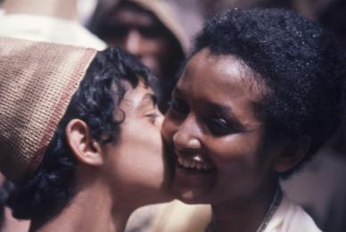 boy in woven cap kissing a woman on the cheek