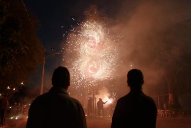 silhouettes of two people looking up at fireworks and sparks in the air