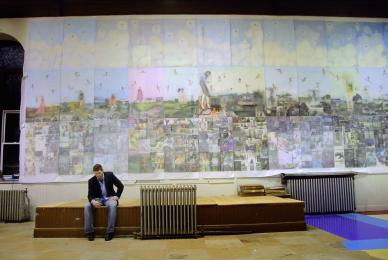 man sitting on bench in front of large mural