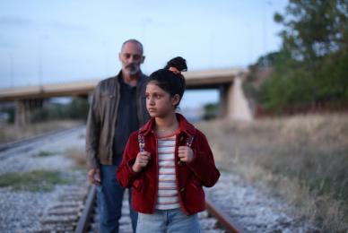 man and young girl walking along railroad tracks