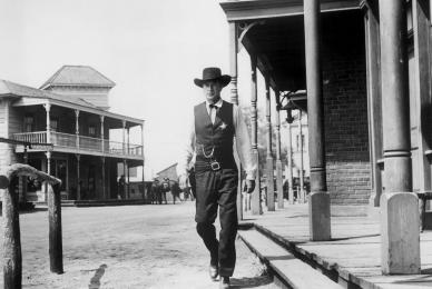 Man with cowboy hat walking down Western street