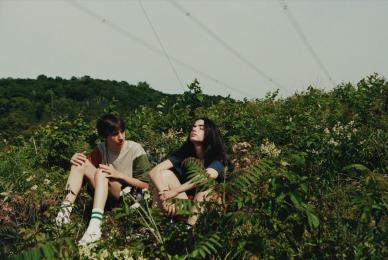 two young people sitting in grassy hill