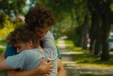two boys hugging on sidewalk outside