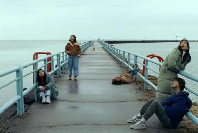 young people sitting on bridge near ocean