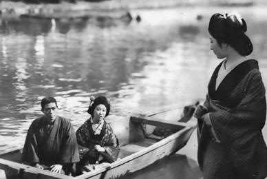 man and woman in rowboat looking at woman on shore