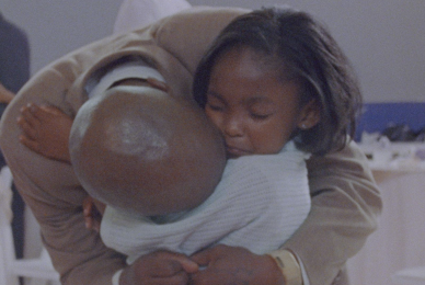 man leaning down to hug young girl