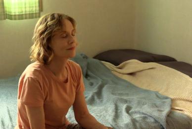 woman sitting on edge of bed with eyes closed peacefully