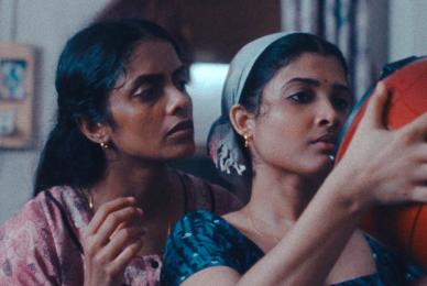 woman standing behind woman who is holding large red bucket