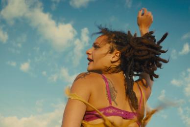 woman in bathing suit with hair flying around and arm up