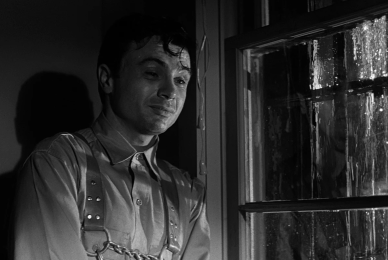 black and white image of man in jail cell near barred window