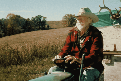 man driving tractor with cowboy hat on 
