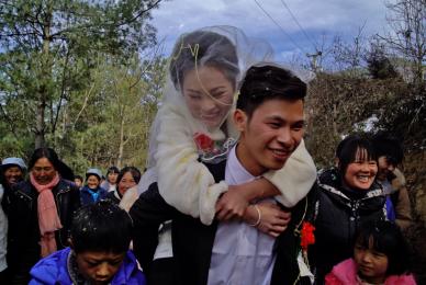 couple getting married outside with woman on man's back and people clapping behind them